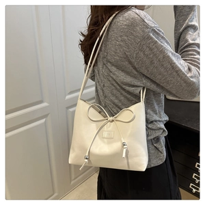 Detailed macro of white minimalist shoulder bag with bow drawstring and silver metal beads