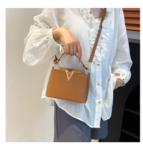 Gros plan du sac à main en cuir marron avec logo V doré et bandoulière réglable élégante