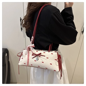 Détail du sac à bandoulière avec nœuds rouges et pendentif en ruban de dentelle chic