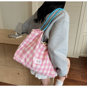 Pink and white checkered knit drawstring bag with woven blue shoulder strap details