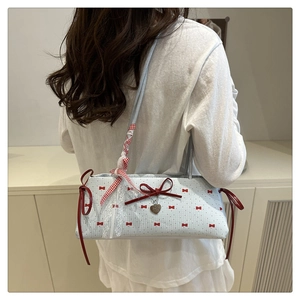Détail du sac à bandoulière bleu clair avec nœuds rouges, dentelle et cœur