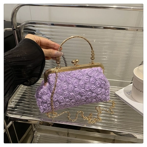 Detail der lila Abendtasche mit 3D-Rosentextur, goldenem Clipverschluss und Henkel