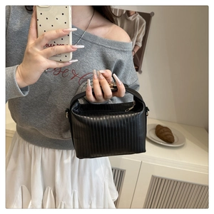 Detailed view of black vertical pleated texture on small crossbody bag with gold hardware
