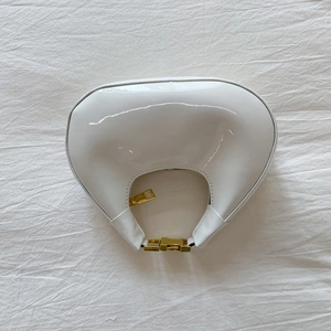 Vue de dessus du sac lune en cuir verni blanc avec zip doré et boucle en métal