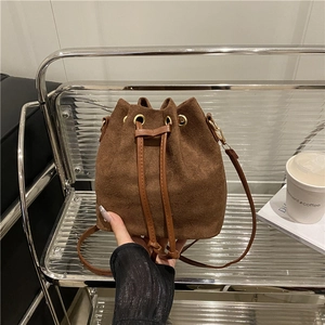 Brown suede drawstring bucket bag with leather strap and gold hardware in a vintage style