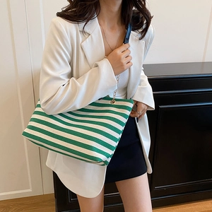 Green and white striped canvas tote bag with chain strap shown with a professional white suit
