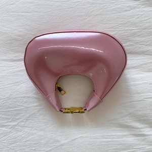 Vue de dessus du sac hobo en cuir verni rose avec finition brillante et zip doré