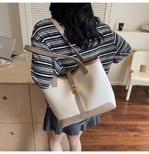 Detailed close-up showing the large capacity cream and brown tote bag worn on a shoulder