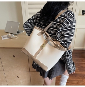 Detail of a large cream tote bag with brown trim shown in a cozy home office setting