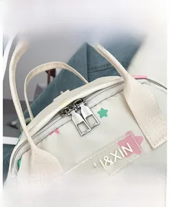 Detailansicht der glatten Metallreißverschlüsse und des Logos auf cremefarbener Tasche