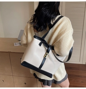 Modern black and white contrast leather tote bag with gold lock shown on model
