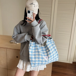Borsa tote in tela a quadretti blu e bianchi con manici rossi in un selfie allo specchio