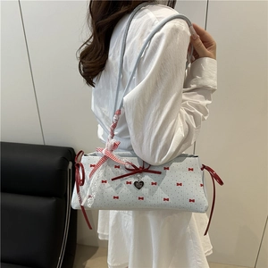 Sac sous le bras bleu clair avec motifs nœuds rouges, dentelle et breloque cœur porté