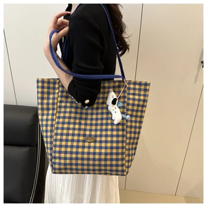 Detail of blue and yellow plaid canvas tote bag with a cartoon puppy pendant