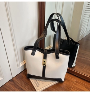 Detail of contrast stitching and gold buckle on a black and white leather tote bag