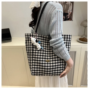 Canvas checkered tote bag detail with vintage gold plaque and plush dog charm