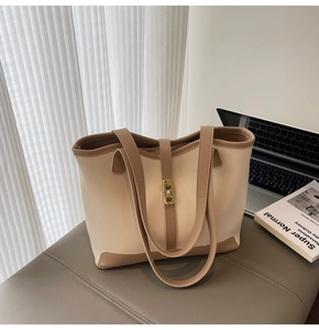 Détail d'un sac cabas bicolore avec un fermoir tournant doré et des finitions en cuir