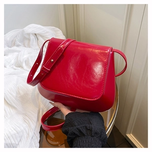 Detail of glossy red faux leather underarm bag with gold metal buckle and adjustable strap