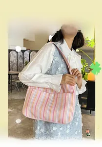 Détail d'un sac cabas rayé en toile avec poches latérales porté par un mannequin en mode