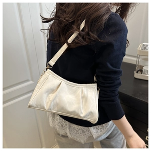Detail view of a white pleated shoulder bag worn on the shoulder with adjustable strap