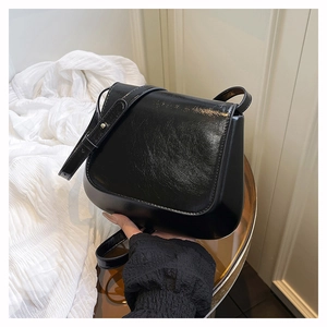 Detailed macro view of the glossy black faux leather texture and adjustable shoulder strap