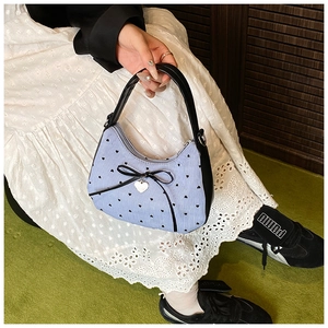 Détail du sac à main rayé avec nœud, pois cœurs noirs et pendentif cœur argenté