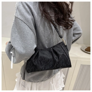 Close-up of black pleated leather underarm bag with refined golden metal hardware