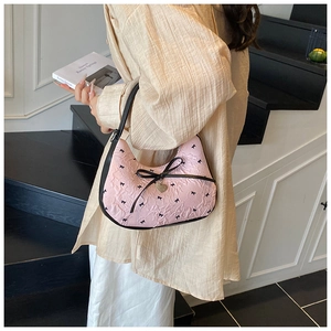 Sac sous le bras rose en forme de croissant avec imprimés nœuds porté à l'épaule