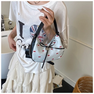 Détail du sac à main blanc avec imprimé nœuds rouges et ruban noir en situation réelle