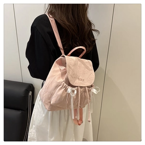 Détail d'un sac à dos rose en nylon avec des nœuds en soie et broderie Nika