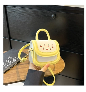 Mini sac bandoulière jaune avec motif cerise rouge et détails dorés tenu à la main