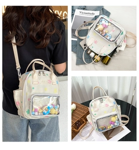 Detailansicht des transparenten Ita-Bag-Fensters mit bunten Plüschkugeln und Badges