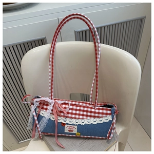 Détail de broderie cerise et dentelle sur un sac à bandoulière en patchwork à carreaux