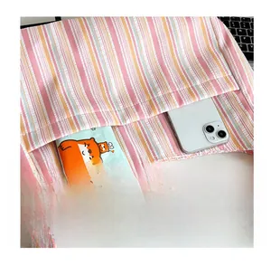 Vue détaillée de la poche avant du sac à bandoulière en nylon rayé contenant un smartphone