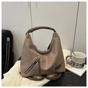 Close-up of brown herringbone hobo bag with leather strap and fashion logo patch