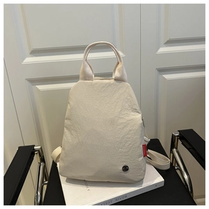Detail of beige nylon backpack featuring side FASHION tag and side profile on leather chair
