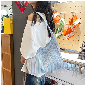 Détail du grand sac fourre-tout en nylon rayé avec poche latérale porté à l'épaule