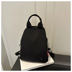 Detailansicht des schwarzen Multifunktions-Rucksacks mit rotem Etikett und Metall-Logo