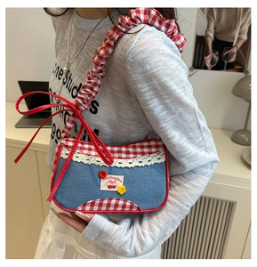 Detail of blue denim handbag with red gingham trim, white lace and a red satin bow