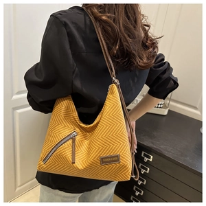 Detail of herringbone pattern texture and leather tag on yellow crossbody tote bag