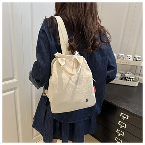 Minimalistischer beiger Nylon-Rucksack, von einem Model lässig getragen