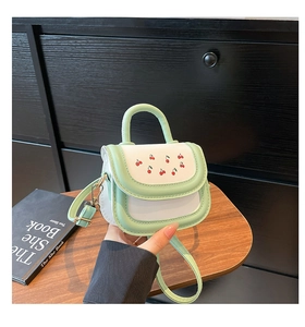 Détail du mini sac vert menthe et blanc avec imprimé cerise et boucles dorées