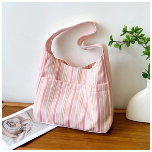 Détail du sac hobo en nylon à rayures colorées avec poche avant sur une table en bois