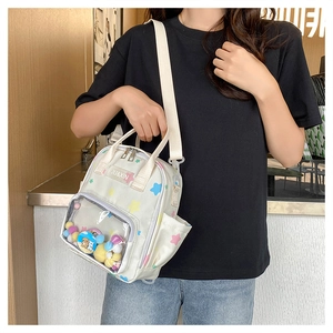 Detail der weißen Segeltuchtasche mit transparentem PVC-Fach und bunten Plüschkugeln innen