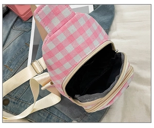 Detailed view of pink plaid crossbody bag with double zippers and ivory nylon strap