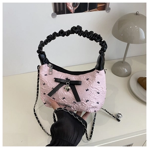 Detail of pink pleated bag with black silk bow, heart pendant and metal chain strap
