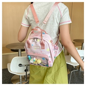 Detail eines rosa Rucksacks mit Sternenmuster und transparentem Fach mit bunten Plüschbällen