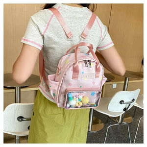 Rosa Mini-Rucksack mit transparentem PVC-Fach, Sternen und bunten Pompons am Modell