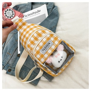 Close-up of yellow checkered crossbody bag with transparent pocket and cute plush toy