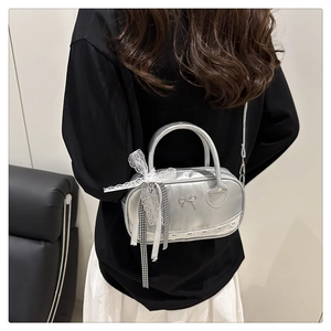 Detail view of silver metallic Boston bag with lace trim and ribbon on model's back
